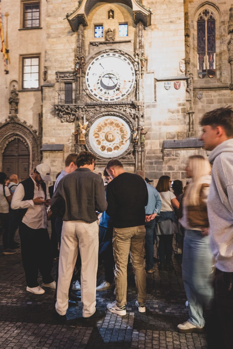 A team playing on their phones beneath the Astronomical Clock at dusk