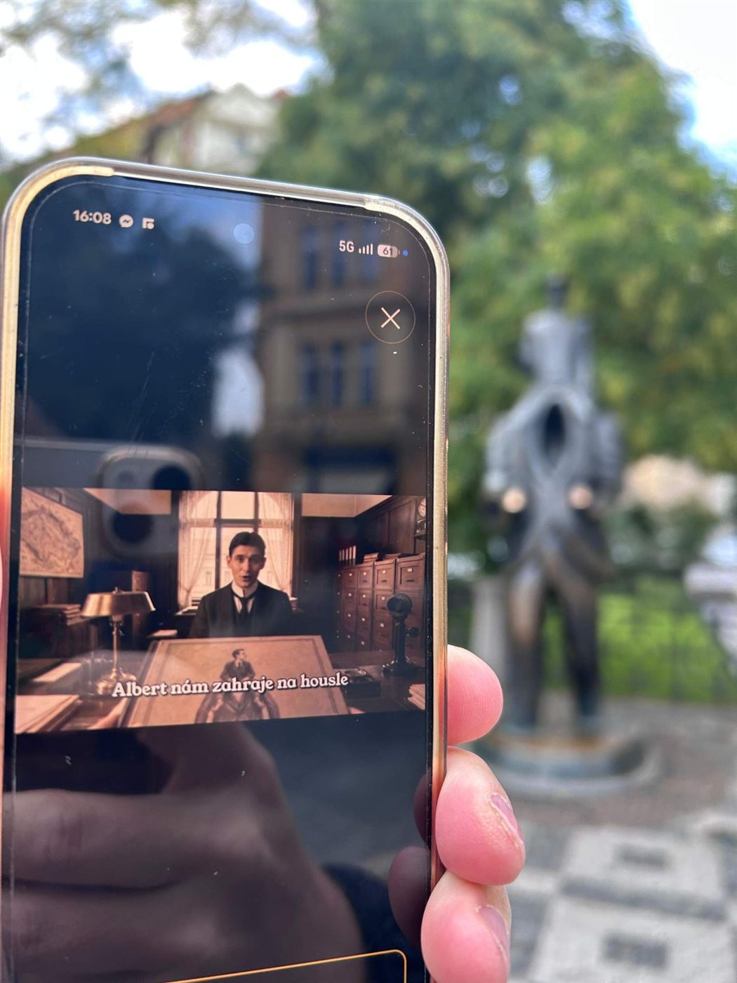 A scene with Franz Kafka on a phone by the Kafka statue