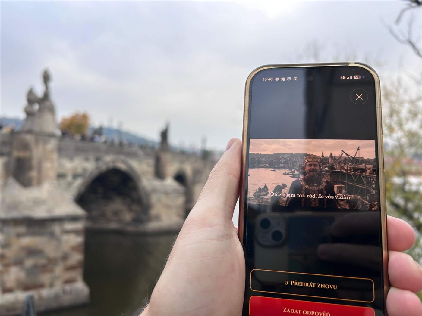 Charles IV on a phone by Charles Bridge, with the real bridge behind